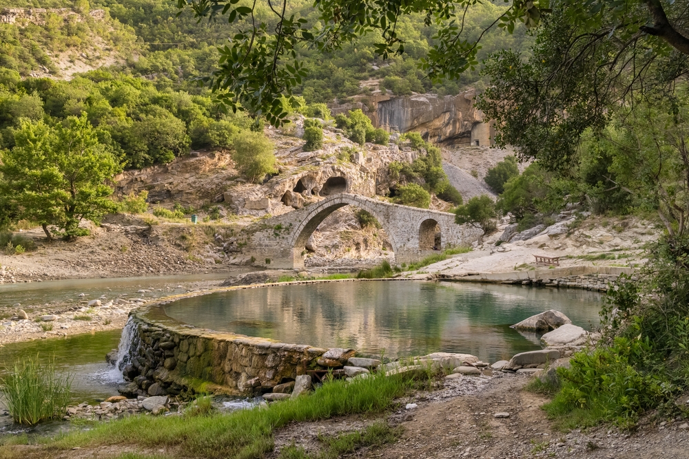 Benja Thermal Baths in Permet, Albania. Pool with hot water and old arch shape stone bridge at background. 